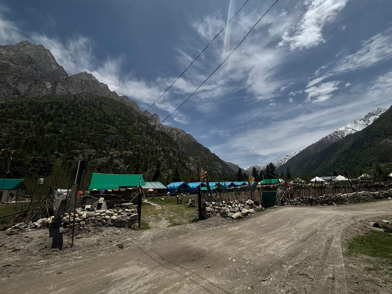 Full property view: blue Swiss tents, green cottages, and dramatic Himalayan peak backdrop