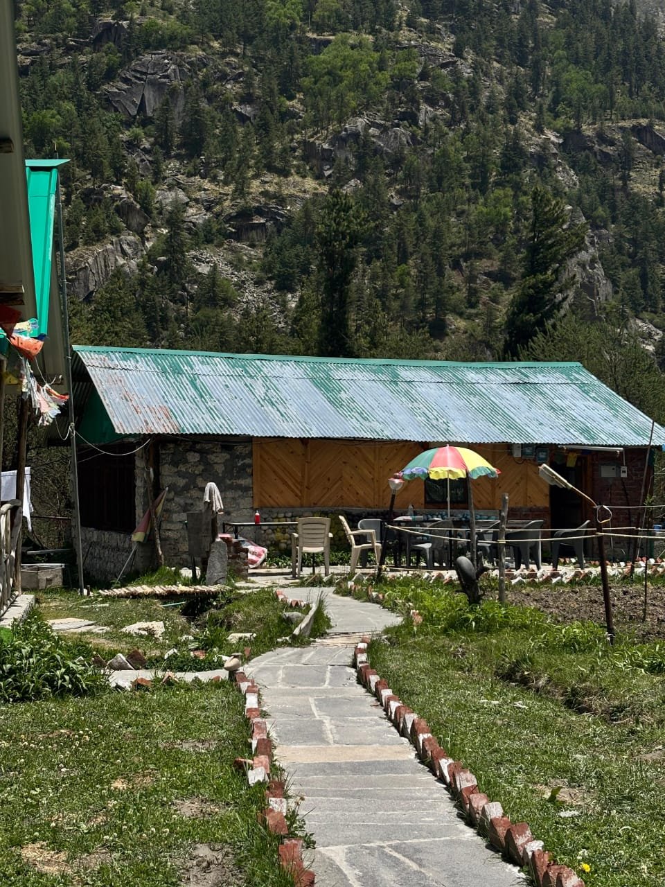 Camp restaurant and dining area with umbrella tables, stone building with mountain backdrop