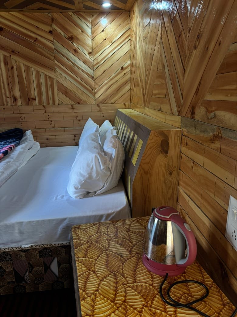 Wooden cottage interior with chevron-pattern cedar panels and kettle on bedside table